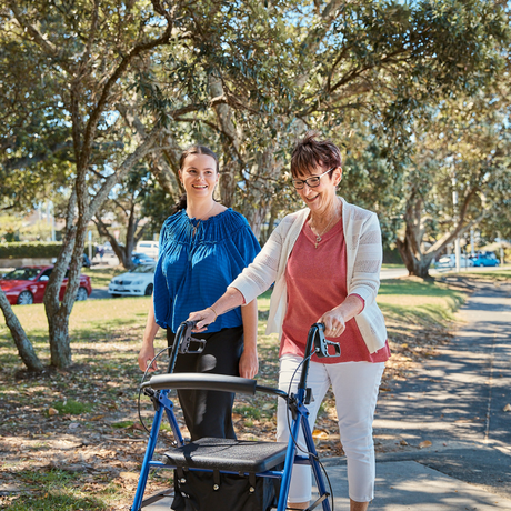 Two women walking in park with one women walking with her AML Four Wheeled 7.3" Castors Rollator