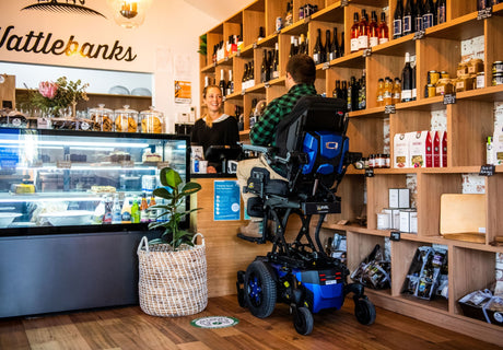 Man in Quantum Powerchair at Cafe Counter